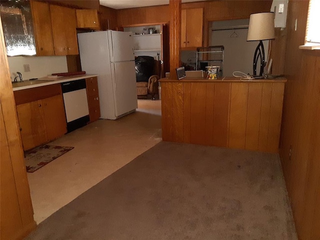 kitchen featuring light countertops, white appliances, brown cabinetry, and a sink