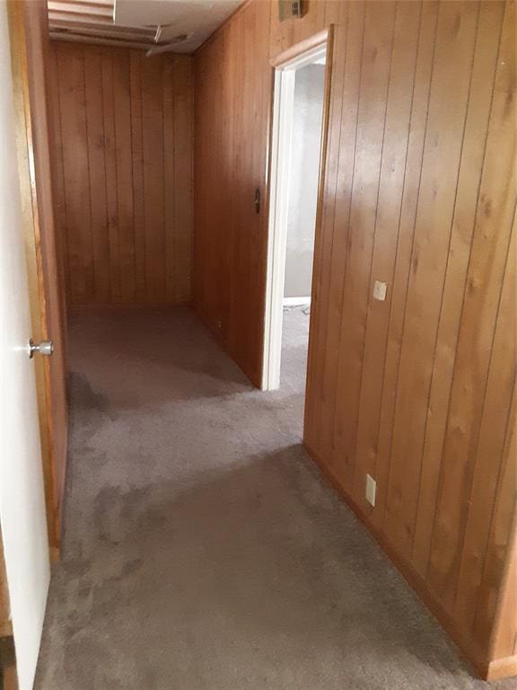 hallway featuring light carpet and wood walls