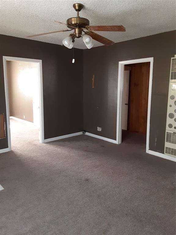 carpeted empty room featuring ceiling fan, a textured ceiling, and baseboards