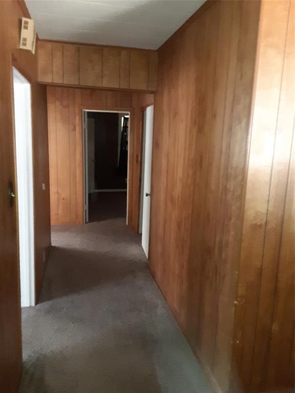 hall featuring light colored carpet and wood walls