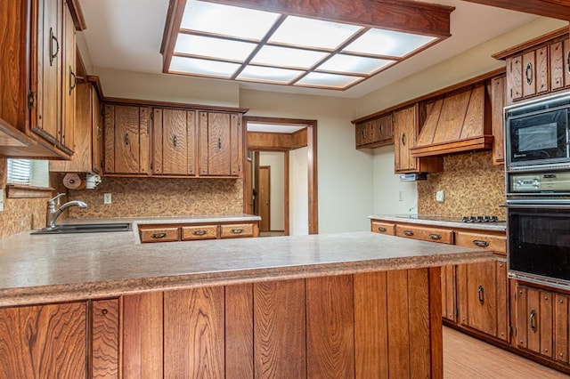 kitchen featuring custom exhaust hood, black appliances, sink, light hardwood / wood-style flooring, and tasteful backsplash