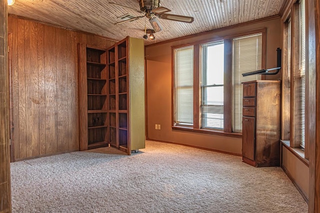 empty room featuring light carpet, ceiling fan, wood walls, and wood ceiling