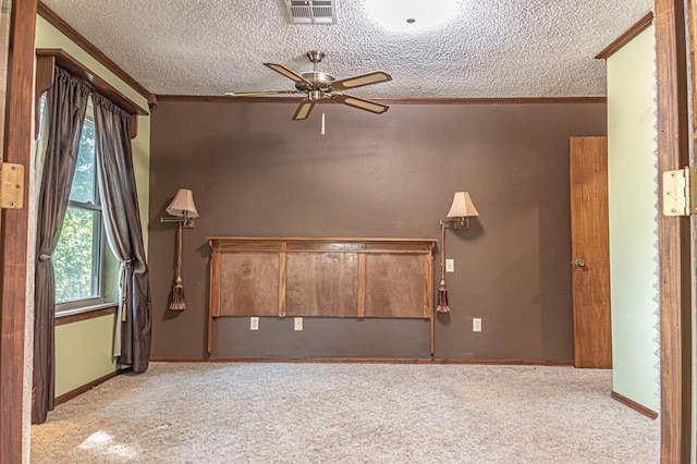 empty room with ceiling fan, light colored carpet, ornamental molding, and a textured ceiling