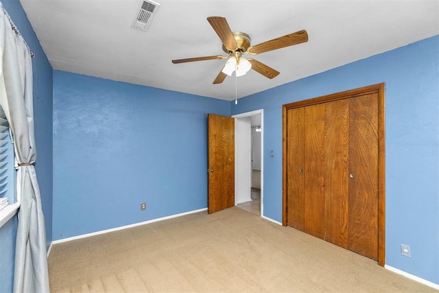 unfurnished bedroom with a closet, light colored carpet, and ceiling fan