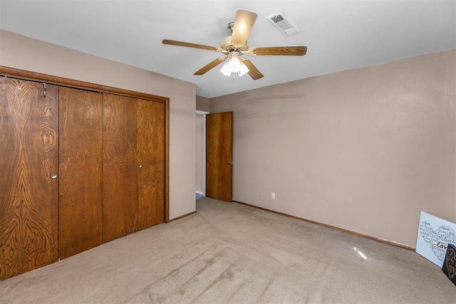 unfurnished bedroom with ceiling fan, a closet, and light carpet