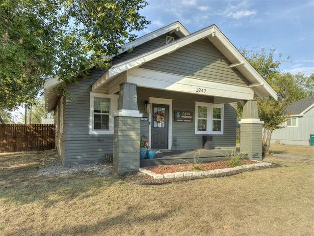 bungalow-style house featuring covered porch and a front lawn