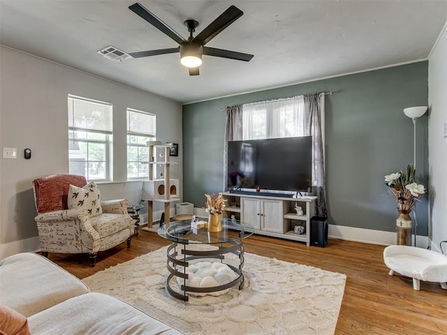 living room featuring hardwood / wood-style floors, a wealth of natural light, ornamental molding, and ceiling fan