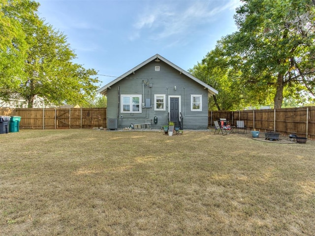 rear view of house with central AC unit and a yard