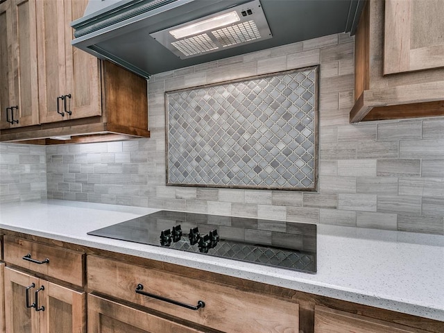 kitchen with decorative backsplash, black electric stovetop, light stone countertops, and custom exhaust hood