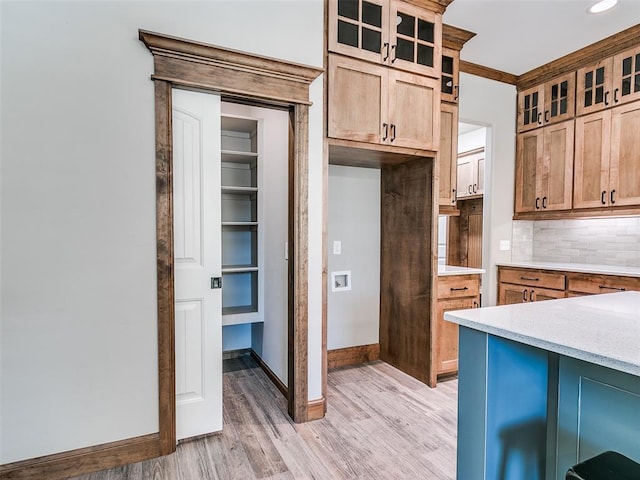 kitchen featuring decorative backsplash, ornamental molding, and light wood-type flooring