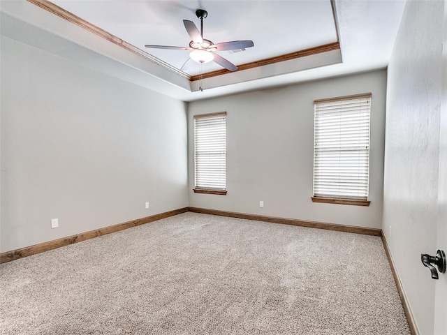 carpeted empty room featuring a tray ceiling, a wealth of natural light, and ornamental molding