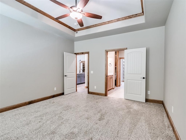 unfurnished bedroom featuring ensuite bath, ceiling fan, sink, crown molding, and a tray ceiling