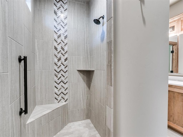 bathroom featuring tiled shower and vanity