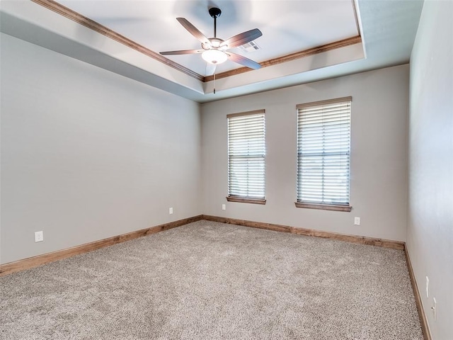 carpeted spare room with a tray ceiling, ceiling fan, and ornamental molding