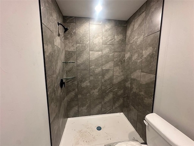 bathroom with tiled shower and toilet