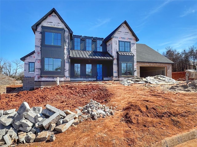 unfinished property with a garage, metal roof, and a standing seam roof