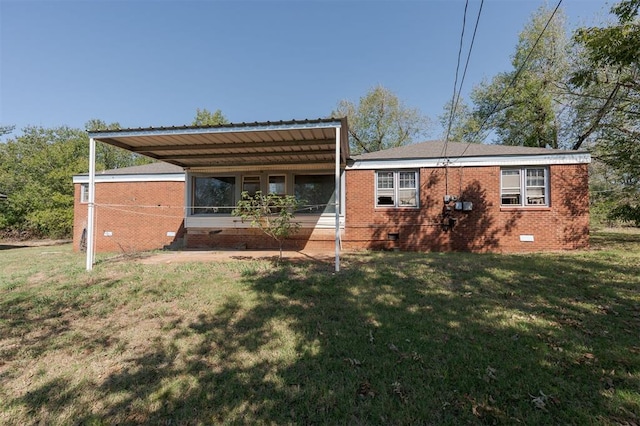 rear view of property with a carport and a yard