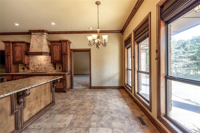 kitchen with a notable chandelier, custom exhaust hood, hanging light fixtures, and a wealth of natural light