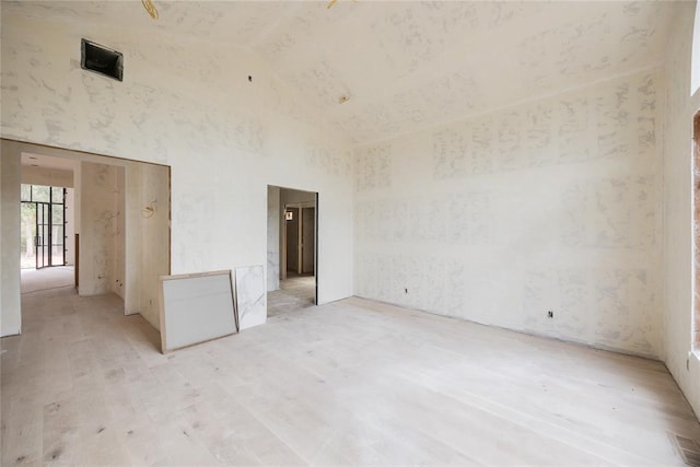 unfurnished room with high vaulted ceiling