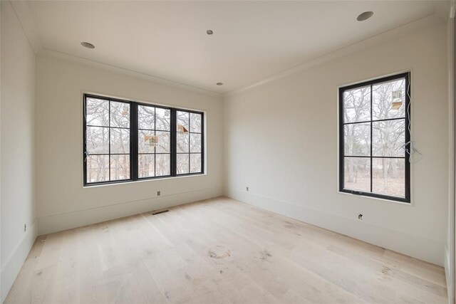 unfurnished room with ornamental molding, a healthy amount of sunlight, and light hardwood / wood-style floors