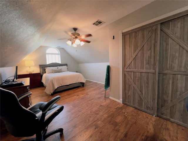 bedroom featuring hardwood / wood-style flooring, ceiling fan, lofted ceiling, and a textured ceiling