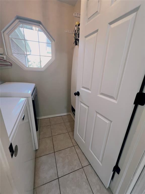 clothes washing area featuring washing machine and clothes dryer and light tile patterned floors