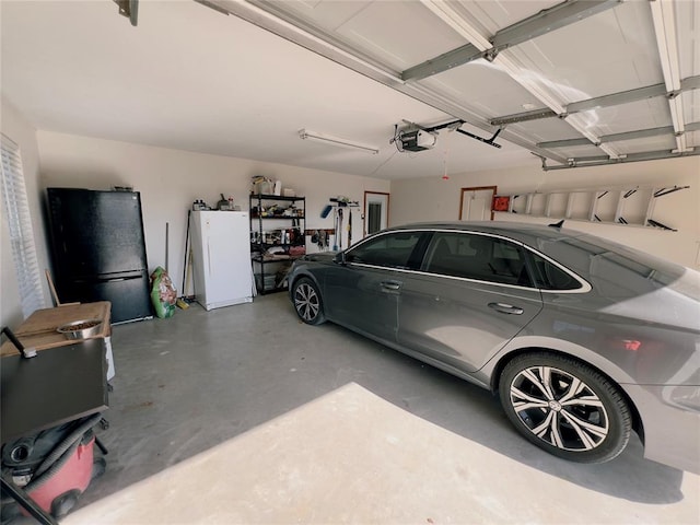 garage with black refrigerator, white refrigerator, and a garage door opener