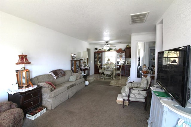 carpeted living room featuring ceiling fan and a textured ceiling