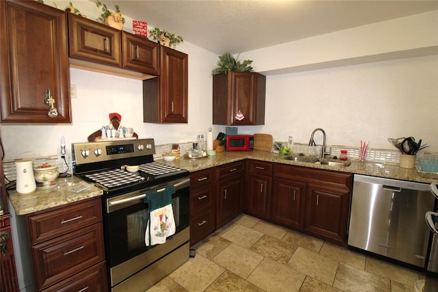 kitchen featuring stainless steel appliances, light stone counters, and sink