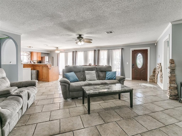 living room featuring a textured ceiling, ceiling fan, and crown molding