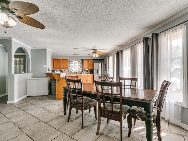 dining space featuring ceiling fan, light tile patterned floors, a textured ceiling, and ornamental molding