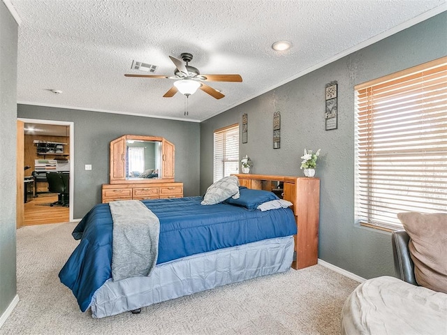 carpeted bedroom with a textured ceiling, ceiling fan, and ornamental molding