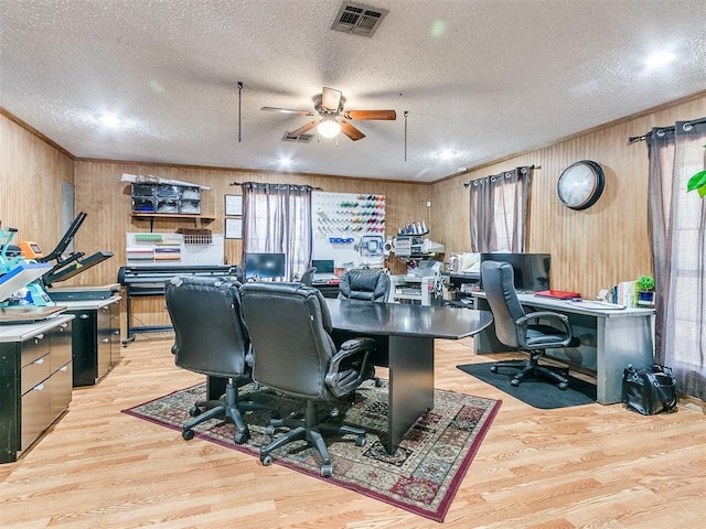 office area with a textured ceiling, light wood-type flooring, and wood walls