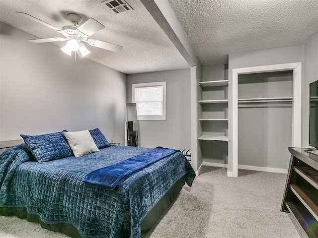 carpeted bedroom featuring ceiling fan, a closet, and a textured ceiling