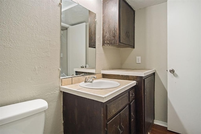 bathroom with hardwood / wood-style floors, vanity, and toilet