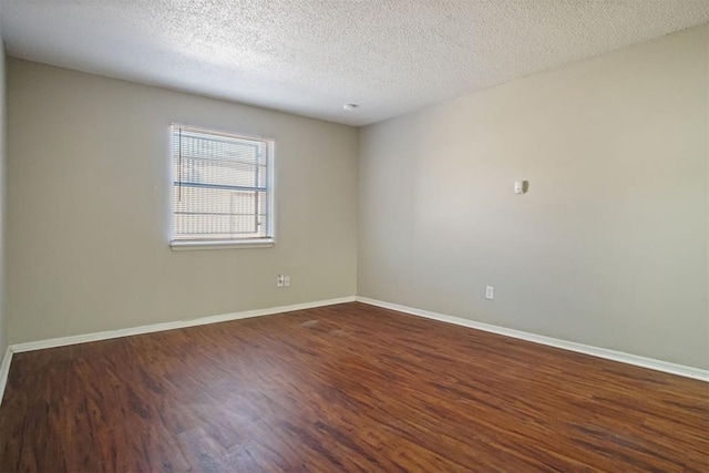 spare room featuring dark hardwood / wood-style flooring and a textured ceiling