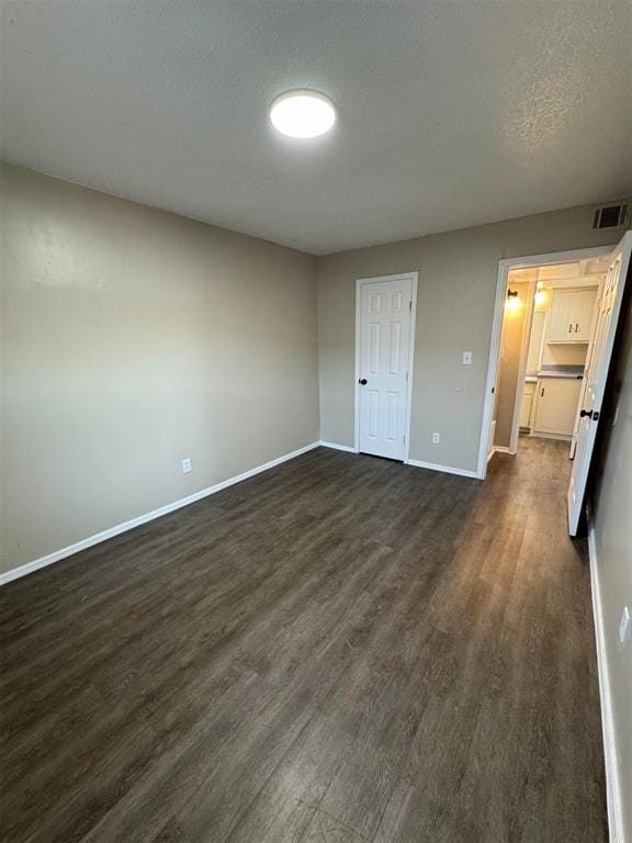 interior space featuring a textured ceiling, a spacious closet, a closet, and dark hardwood / wood-style floors