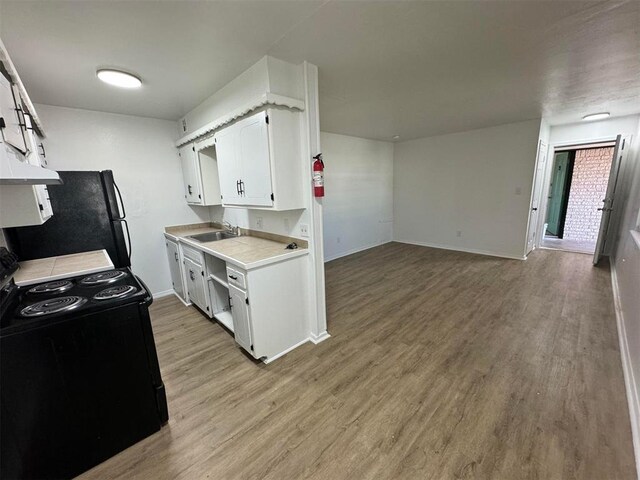 5825 NW 34th St, Oklahoma City, OK 73122 - kitchen with black appliances, a sink, baseboards, light wood-type flooring, and white cabinetry