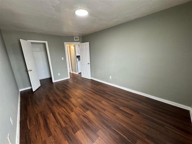 unfurnished bedroom with dark hardwood / wood-style flooring, a textured ceiling, and a closet