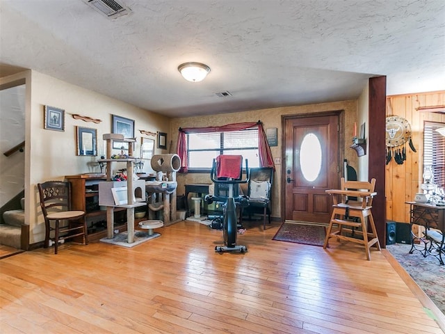 entryway with wooden walls, wood-type flooring, and a textured ceiling