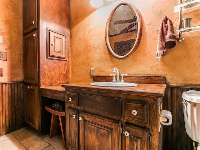 bathroom with vanity, toilet, and wooden walls