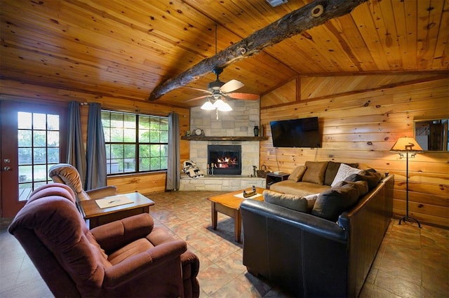 living room with wooden walls, vaulted ceiling with beams, ceiling fan, a fireplace, and wood ceiling