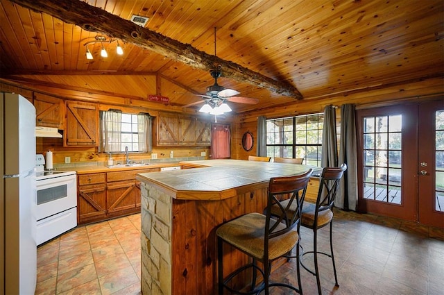 kitchen with a center island, white appliances, wooden ceiling, sink, and vaulted ceiling with beams