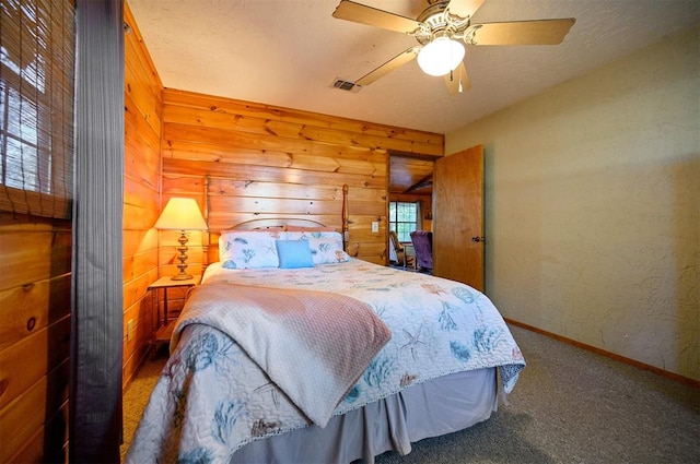 carpeted bedroom with ceiling fan and wood walls