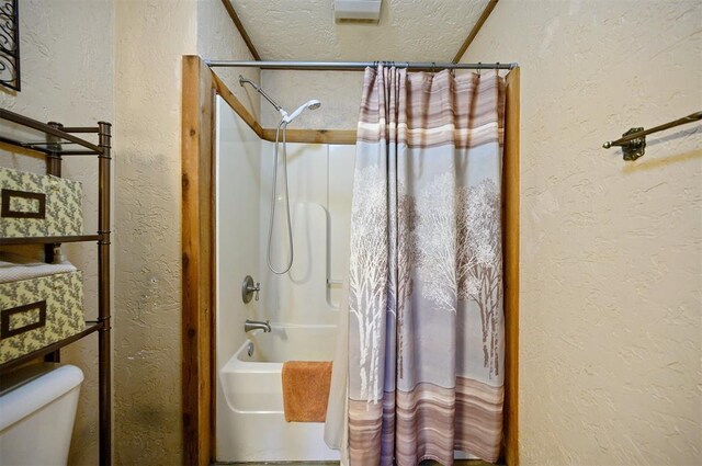 bathroom with toilet, a textured ceiling, and shower / tub combo