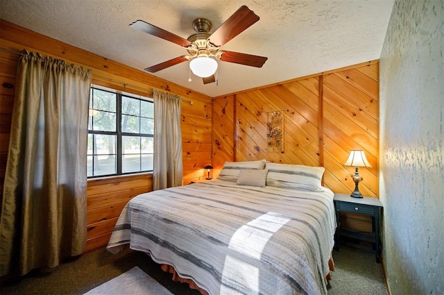 bedroom featuring dark colored carpet, ceiling fan, a textured ceiling, and wooden walls