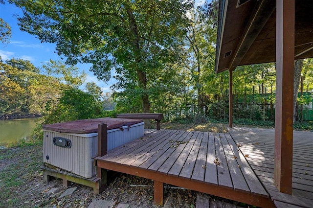 wooden terrace featuring a water view and a hot tub