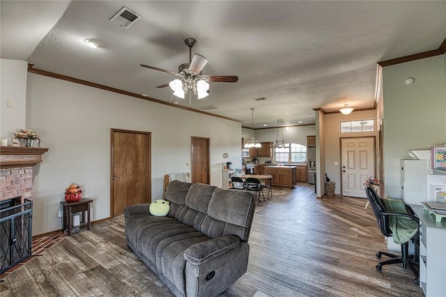 living room with ceiling fan, a fireplace, dark wood-type flooring, and ornamental molding