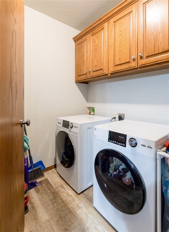 laundry room with cabinets, light hardwood / wood-style floors, and washer and clothes dryer