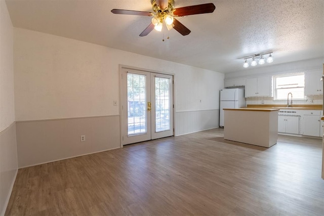 kitchen with white cabinetry, french doors, white fridge, light hardwood / wood-style floors, and a textured ceiling